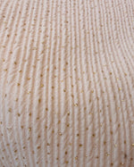 Load image into Gallery viewer, A close-up of a ribbed knit fabric in a light cream or off-white color, decorated with small scattered gold sequins.
